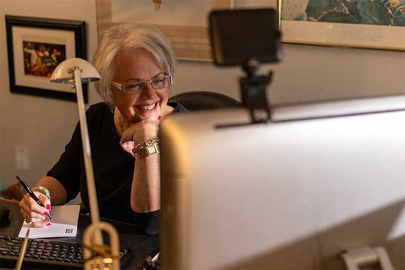 Marsha is smiling in a denim shirt sitting behind her computer