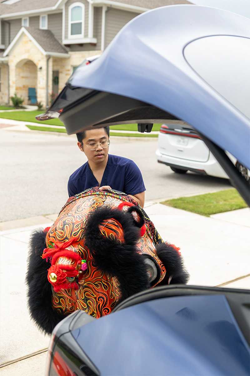 Kevin putting the lion head in his car trunk